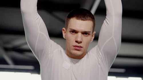 Young Man Stretching Arms Up in Modern Gym Setting