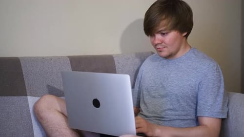 Young Adult Typing on Laptop Computer on Couch