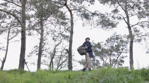 Young soldier in uniforms and tactical vest works in the forest and prepares for action