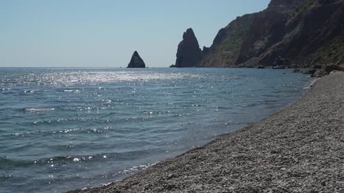 Seascape Beach Water Calm Blue Ocean Waves Gently Lapping a Serene Pebble Beach with Stunning Rock