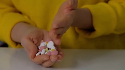 Female Hand Sorts Out Different Pills Pills on a White Table Shows Pills Vitamins or Drugs Tablets