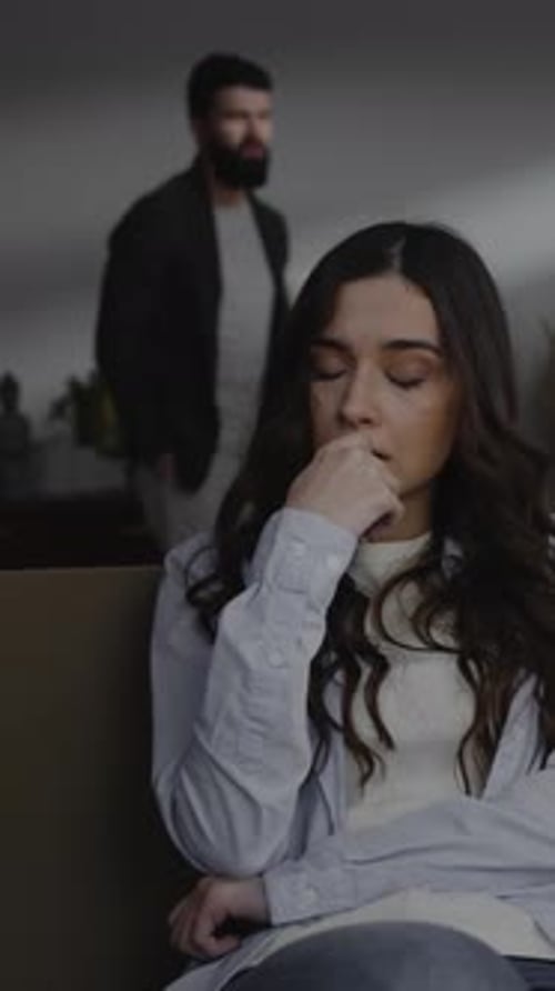 Upset Woman Sitting as Man Gestures in Background
