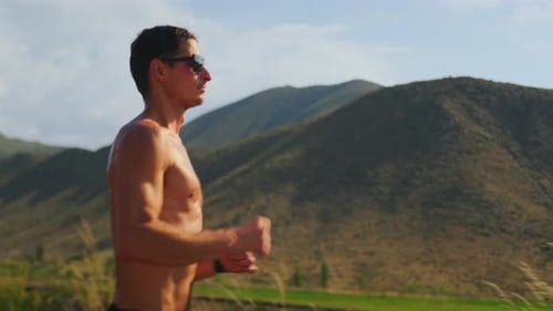 Muscular Shirtless Man Runs Through Mountains Building Endurance and Strength