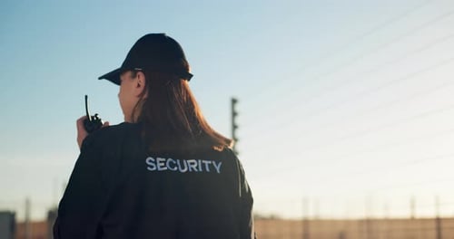 Security Guard with Walkie Talkie Standing Watchful Outside
