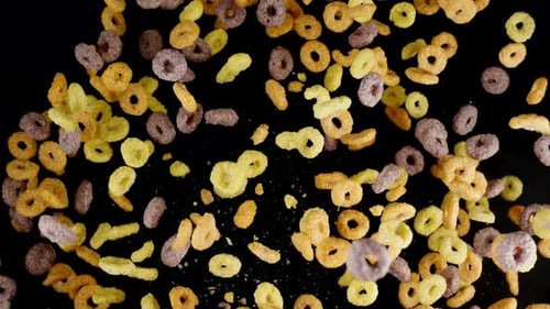 Vibrant Cereal Loops Falling in Slow Motion on Black Background