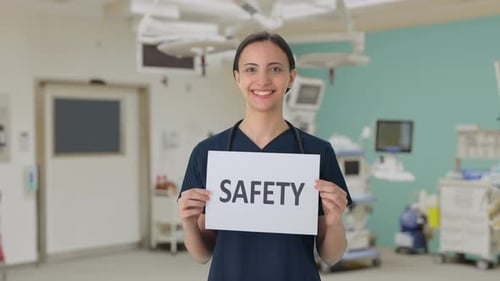 Woman in Scrubs Holding Safety Sign in Operating Room
