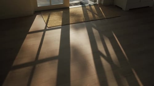 Warmes Sonnenlicht wirft Fensterschatten auf den Holzboden. Ideal für Wohndekorationen oder Lifestyle-Projekte.