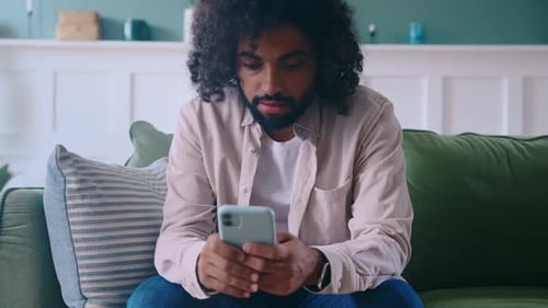 Excited Man Celebrates with Phone on Couch