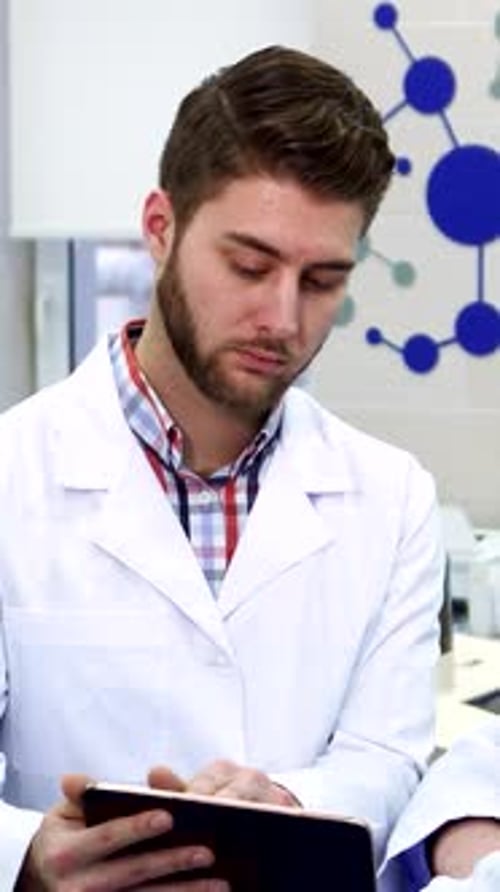 Engagierte männliche Wissenschaftler arbeiten in einem modernen Labor an einem Tablet zusammen