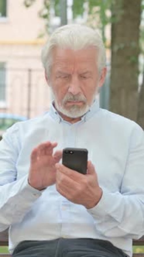 Senior Man Using Smartphone Sitting on Park Bench