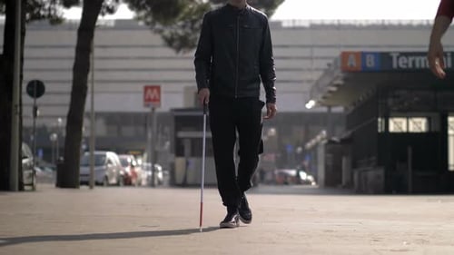 blind young man walking with his stick in the city.Blindness,indipendence