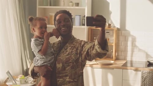 Man in Uniform Taking Selfie with Young Child
