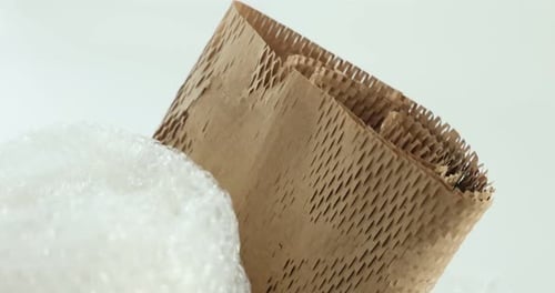 Different packaging materials on white background, closeup. Camera moving down
