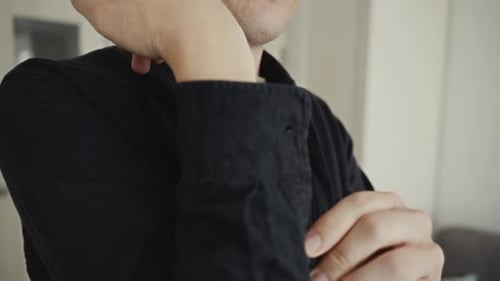 Man Buttoning his Sleeve in a Home