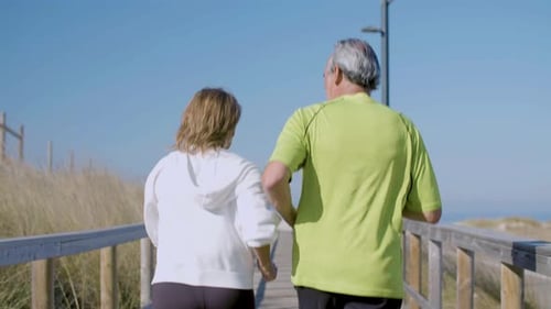 Man and Woman in Sportswear Jogging Along Wooden Path Outdoor