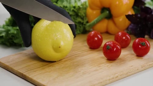Der Koch schneidet die frische Zitrone mit einem Messer auf einem Schneidebrett in Zeitlupe