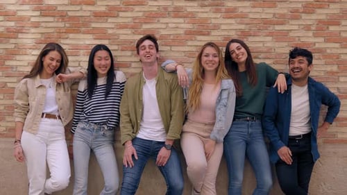 Smiling Friends Posing Against Brick Wall Outdoors