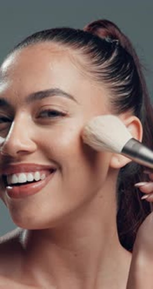 Face, woman and smile with makeup brush in studio with beauty, foundation and aesthetic