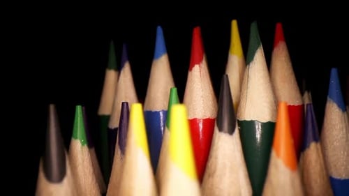 panning right past colored pencils, 3rd and 4th rows are in focus. moving laterally past a jar of co