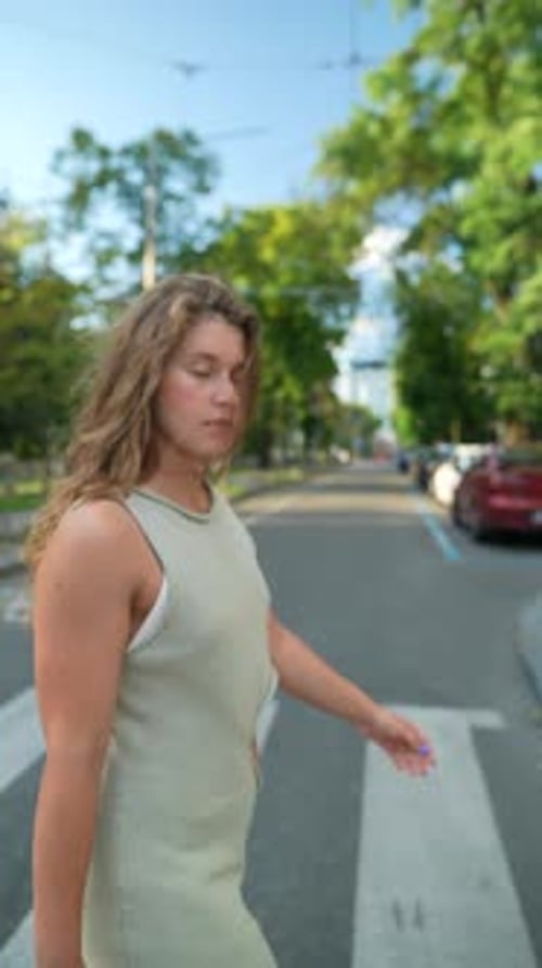 A Beautiful Girl's Red Curly Hair Stands Out As She Strolls Through the Sunsoaked Evening City