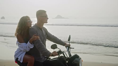 Man Woman in Love Sit on Motorcycle By Sea on Beach Enjoy Sunset Girlfriend Embraces Strokes Kisses