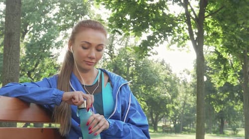 Woman Drinks Water After Workout in Park