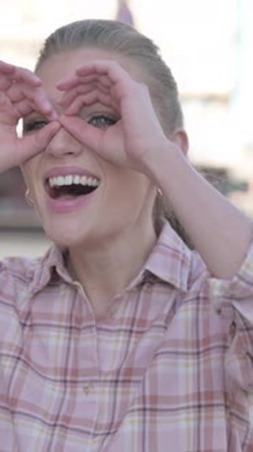 Junge Frau schaut sich mit handgemachtem Fernglas im Freien um, vertikales Video