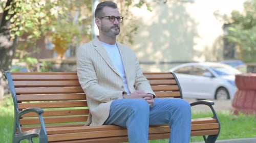 Man Sitting Calmly on Park Bench in Sunlight