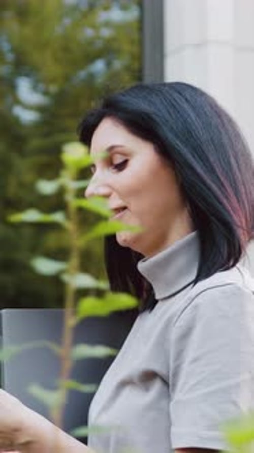 Side View of Confident Young Caucasian Woman Holding Laptop and Using Smartphone Professional Female