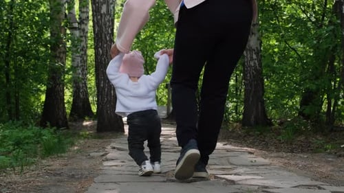 Young Mother Teaching Baby to Walk in Open Air