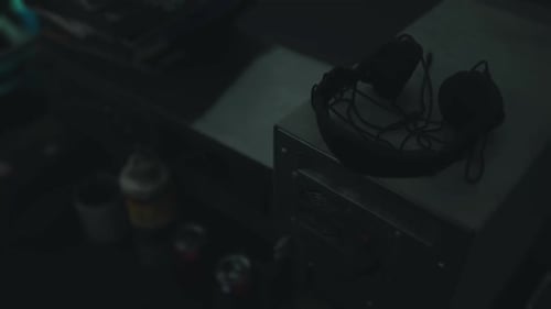 Headphones Resting on a Desk Next to Various Objects in a Dimly Lit Space