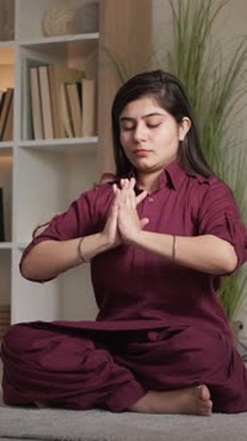 Young Adult Meditates in Lotus Position Indoors