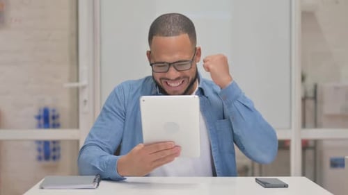 Man Celebrates Good News on Tablet Device