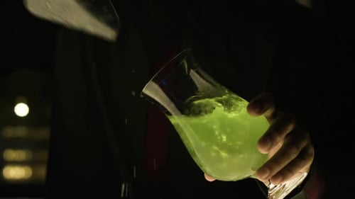 Barkeeper fügt etwas Eis in ein Glas grüne Margarita