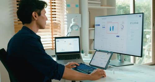 Adult works at desk with three screens