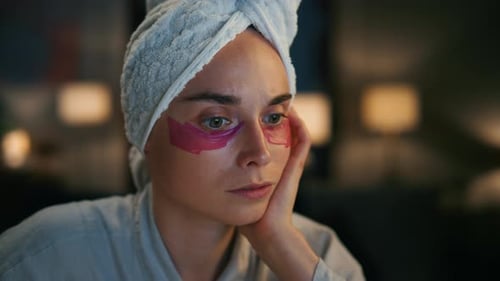 Woman with eye patches and towel on head