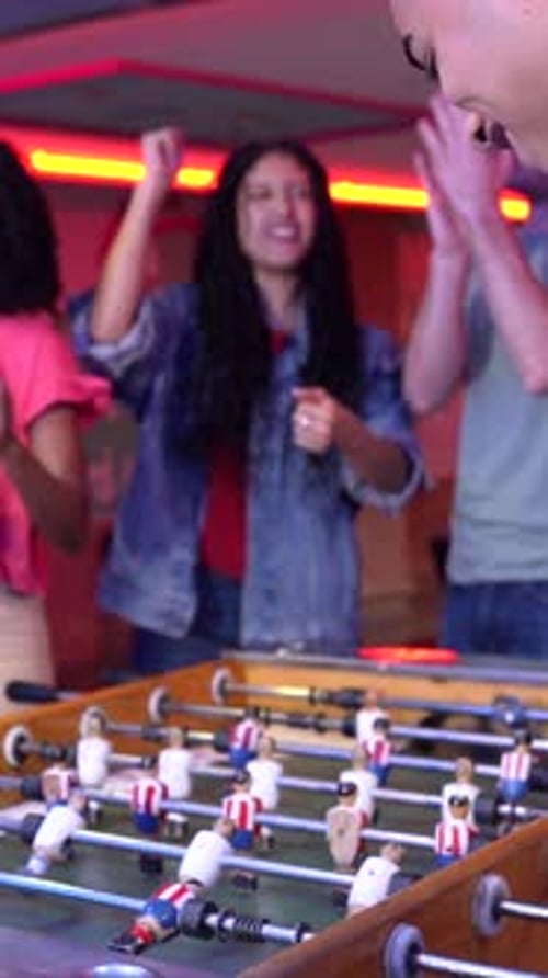 Friends Playing Foosball Table Soccer in an Arcade