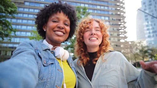 Two Smiling Women Waving in Urban Setting