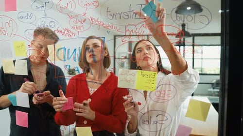 Collaborative Team Brainstorming Ideas on Glass Wall