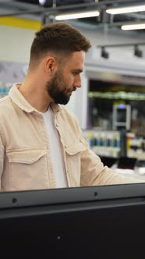 Customer Using Self Checkout Kiosk in Modern Supermarket