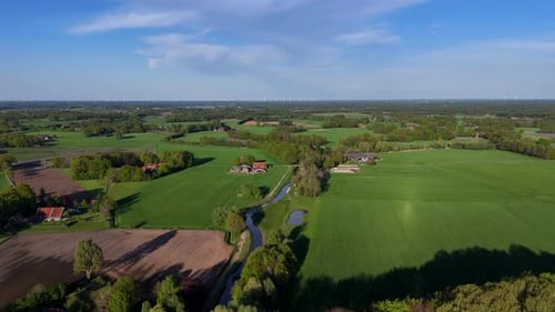 Tranquil river stream between rural farm fields and countryside houses. Aerial forward wide shot. Su