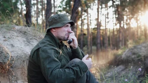 A soldier in uniform emotionally communicates with command via radio.