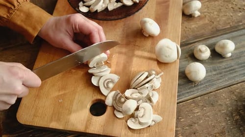 Slicing fresh mushrooms on a wooden cutting board