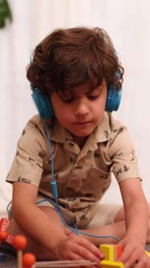Young Boy Playing with Building Blocks While Listening to Music
