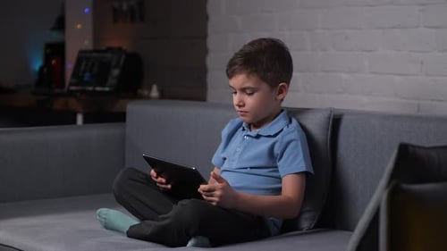 Young Boy Using a Tablet on Couch at Home