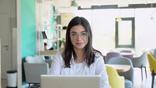 Happy Young Girl Working at a Coffee Shop with a Laptop