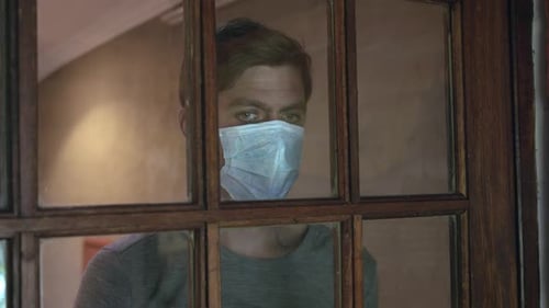 Man Wearing Mask Looks Through Window