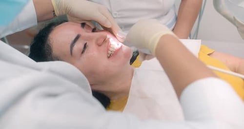 Woman Dentist Works with a Microscope in Mouth of Patient's Cavity in Dental Office on Installation