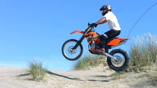 Man Riding Motocross on Sand Dune in Daytime
