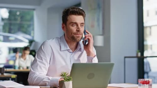 Man Talking on Phone While Typing at Desk